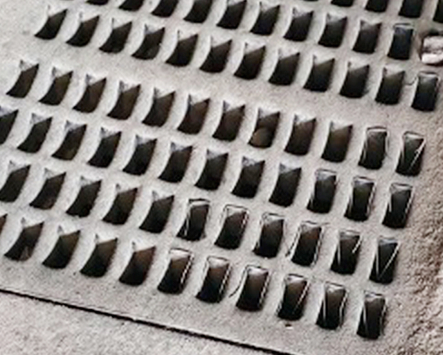 Close-up view of the slight wear on the surface of Strudex rubber screen panel after extensive use, demonstrating no hole plugging in the screening area due to dual hardness material application.