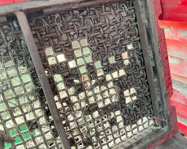 Clogged aggregate screening equipment showing visible signs of plugging, highlighting the common challenges in mineral processing.